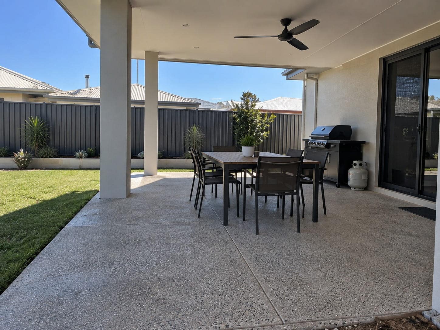 Covered alfresco with a dining setting on an exposed aggregate floor