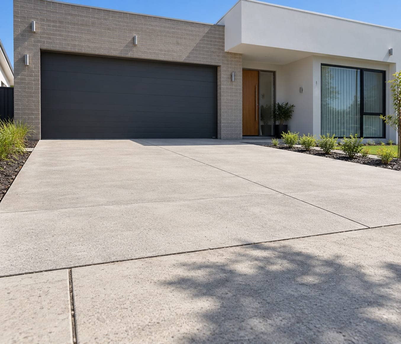 New broom-finished concrete driveway with neat control joints leading to a double garage at a modern Canberra home