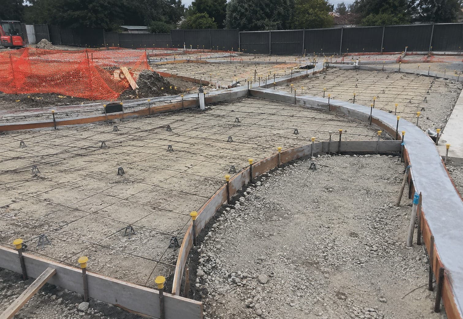 Steel reinforcing mesh on bar chairs inside timber formwork, ready for new concrete sections on a Canberra site