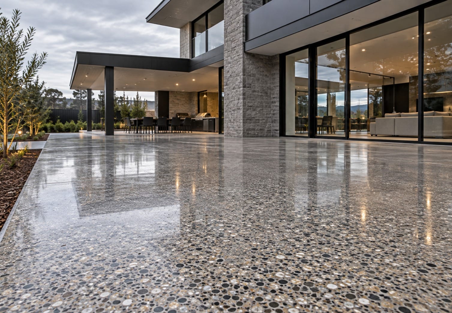 Polished concrete with exposed stone running from the living room out under the covered alfresco of a modern Canberra home