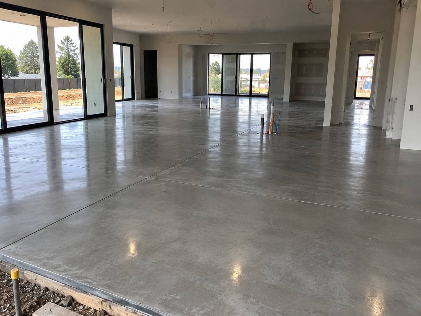 Freshly finished residential concrete floor slab with service penetrations inside an open-plan Canberra home under construction