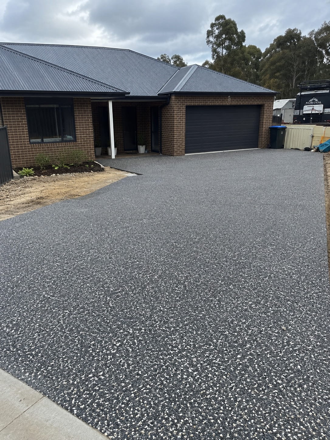 Charcoal exposed aggregate driveway leading to a brick home in Canberra